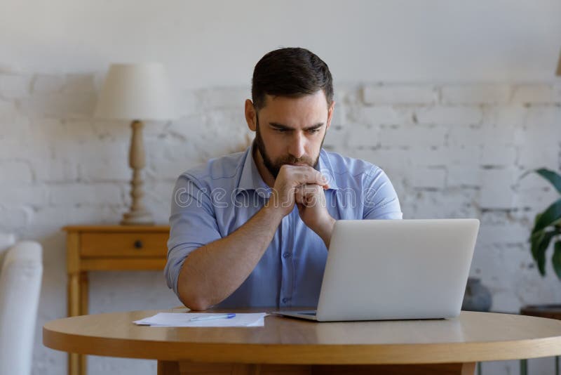 σοβαρός άνδρας διαβάζει email στην εμφάνιση φορητού υπολογιστή που ανησυχεί ή προβληματίζεται στοκ εικόνα