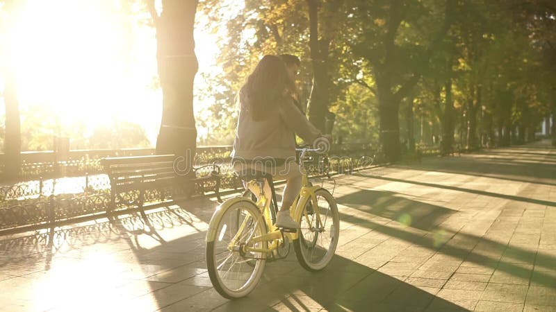 Σπάνια άποψη ενός νέου ευτυχούς ζεύγους ή των φίλων που οδηγά τα ποδήλατά τους στο κενή πάρκο ή τη λεωφόρο πόλεων στο καλοκαίρι