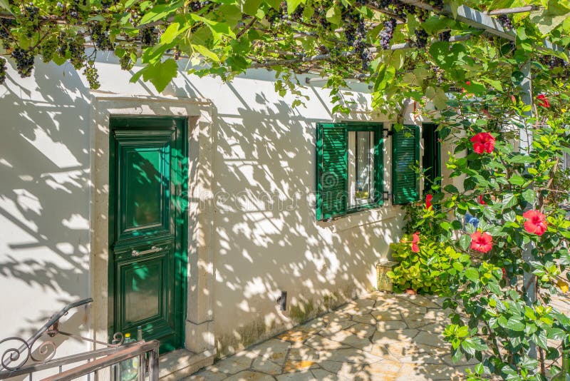 GREECE - CORFU - BARBATI - AUGUST 1, 2018: House with a pergola with grape plants. GREECE - CORFU - BARBATI - AUGUST 1, 2018: House with a pergola with grape plants.
