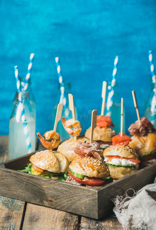 Σπιτικά burgers στον ξύλινο δίσκο και λεμονάδα στα μπουκάλια γυαλιού στοκ φωτογραφία