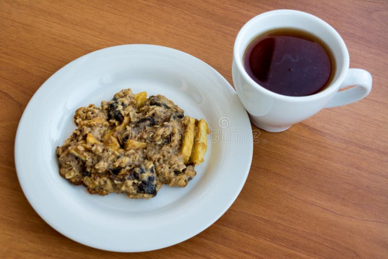 Σπιτικά oatmeal μπισκότα στο πιάτο με την ΚΑΠ του τσαγιού στοκ φωτογραφία με δικαίωμα ελεύθερης χρήσης Σπιτικά oatmeal μπισκότα στο πιάτο με την ΚΑΠ του τσαγιού στοκ φωτογραφία με δικαίωμα ελεύθερης χρήσης