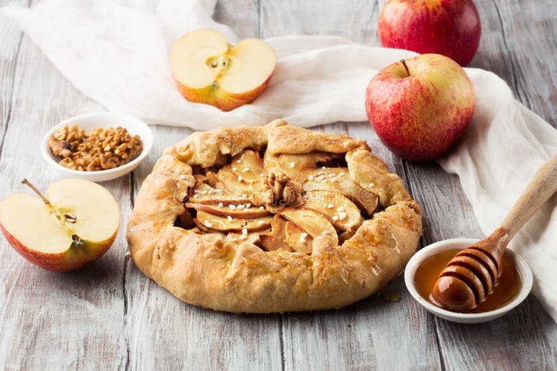 Homemade crostata with ripe apples, nuts and maple syrup on rustic white wooden background, selective focus. Homemade crostata with ripe apples, nuts and maple syrup on rustic white wooden background, selective focus