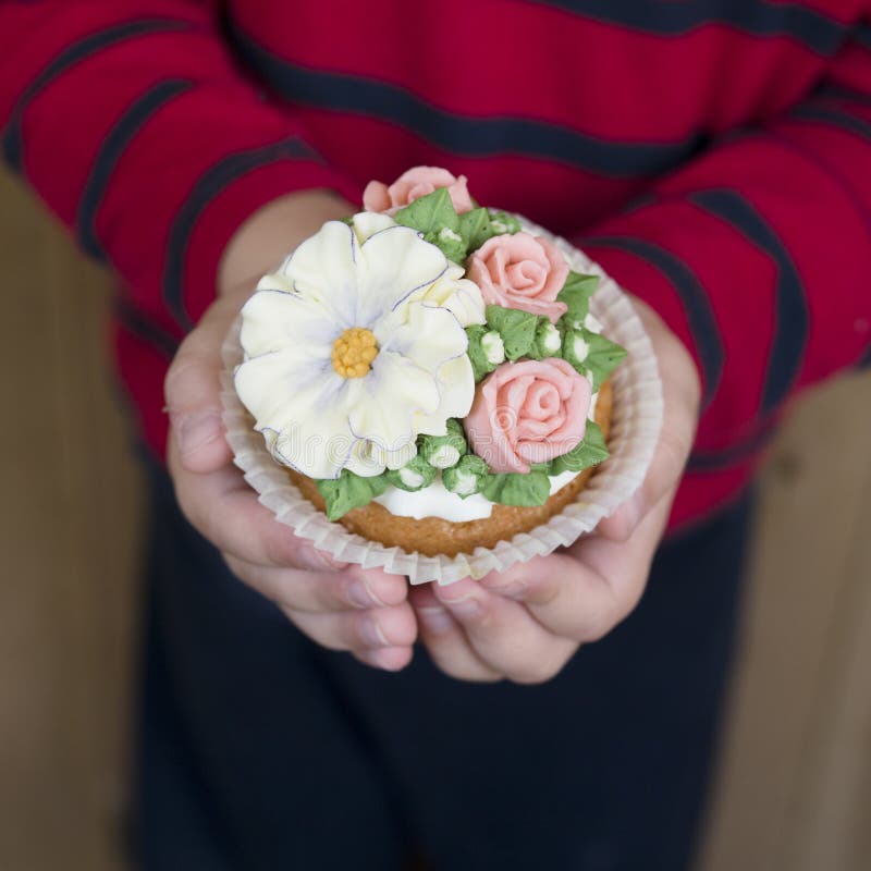 Σπιτικό σφουγγάρι cupcakes με τα λουλούδια buttercream που παγώνουν Το αγόρι κρατά διακοσμημένος cupcake Γλυκό δώρο στο mom στοκ εικόνες με δικαίωμα ελεύθερης χρήσης Σπιτικό σφουγγάρι cupcakes με τα λουλούδια buttercream που παγώνουν Το αγόρι κρατά διακοσμημένος cupcake Γλυκό δώρο στο mom στοκ εικόνες με δικαίωμα ελεύθερης χρήσης