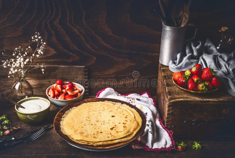 Σπιτικός crepes στο σκοτεινό αγροτικό πίνακα κουζινών με τις φράουλες και το γιαούρτι στα κύπελλα στοκ φωτογραφία με δικαίωμα ελεύθερης χρήσης