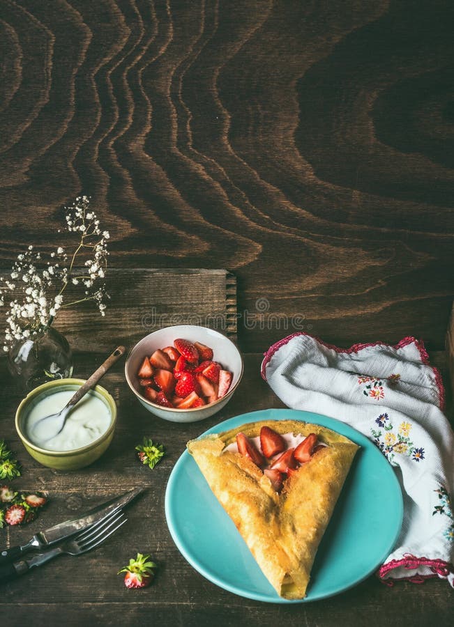 Σπιτικός crepes στο σκοτεινό αγροτικό πίνακα κουζινών με τις φράουλες και το γιαούρτι στοκ εικόνες με δικαίωμα ελεύθερης χρήσης