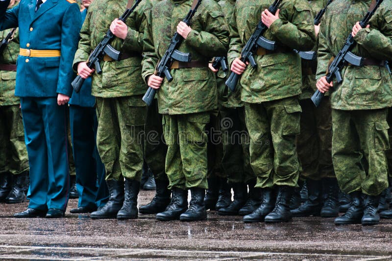 Soldiers in camouflage stand in formation with officer in blue clothing. Soldiers in camouflage stand in formation with officer in blue clothing