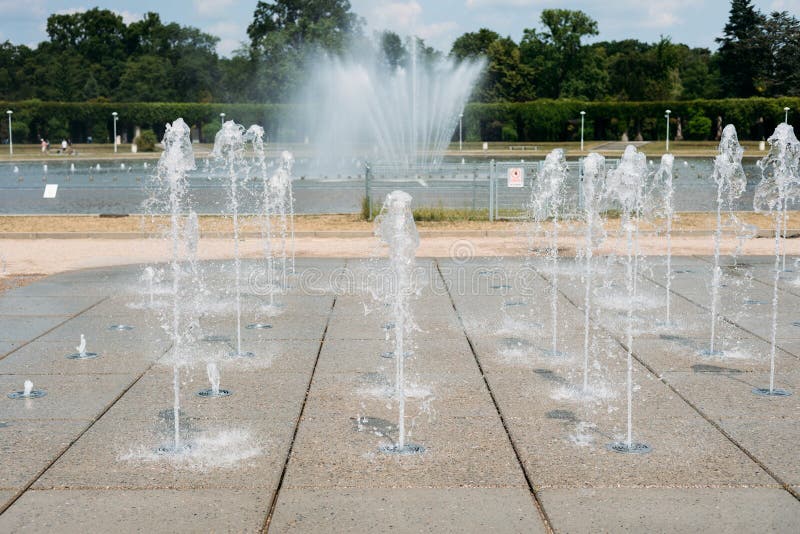 Water droplets spread from the fountain in the air. Splashing water from a fountain in the park. Water droplets spread from the fountain in the air. Splashing water from a fountain in the park