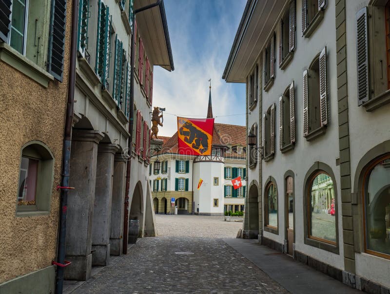 Narrow street and flag of canton of Bern in Thun, Switzerland Thun city is a popular travel destination and tourist attraction in Switzerland, town, window, cobblestone, traveling, hotel, cultural, architectural, swiss, tower, downtown, scene, medieval, cityscape, idyll, no, amazing, spectacular, archway, pavement, daylight, houses, age, place, sky, clouds, picturesque, cafe, public, wide, mirror, reflection, column, jalousie, shade, sidewalk, roof, tiled, lantern. Narrow street and flag of canton of Bern in Thun, Switzerland Thun city is a popular travel destination and tourist attraction in Switzerland, town, window, cobblestone, traveling, hotel, cultural, architectural, swiss, tower, downtown, scene, medieval, cityscape, idyll, no, amazing, spectacular, archway, pavement, daylight, houses, age, place, sky, clouds, picturesque, cafe, public, wide, mirror, reflection, column, jalousie, shade, sidewalk, roof, tiled, lantern