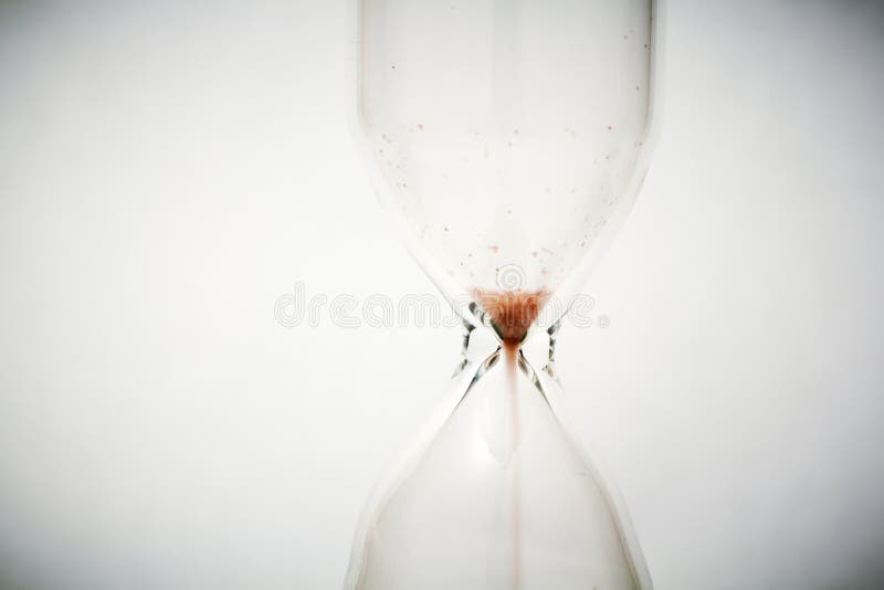 Close view of sand flowing through an hourglass. Close view of sand flowing through an hourglass.