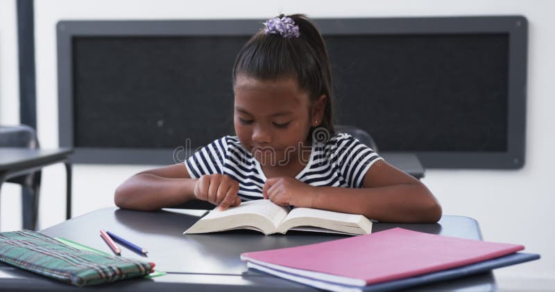 στο σχολείο σε μια τάξη μια νεαρή αφρικανή αμερικανίδα επικεντρώνεται στην ανάγνωση ενός βιβλίου