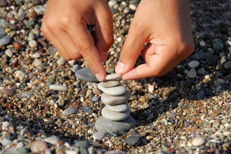 Child hands building a rocks stack carefully. Child hands building a rocks stack carefully