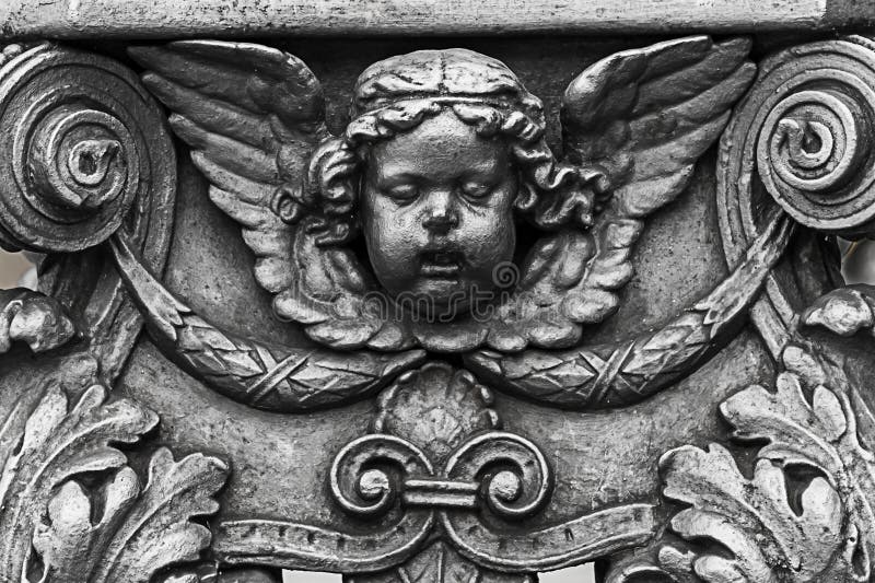 Στοιχεία ντεκόρ χαλκού που διακοσμούν το γλυπτό του κεφαλιού του αγγέλου Cupid με τα λογαριασμένα φτερά των μονογραμμάτων με ένα στοκ εικόνες Στοιχεία ντεκόρ χαλκού που διακοσμούν το γλυπτό του κεφαλιού του αγγέλου Cupid με τα λογαριασμένα φτερά των μονογραμμάτων με ένα στοκ εικόνες