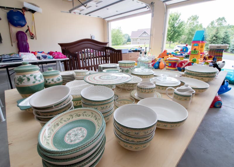 Tables full of dishes, toys, and children`s clothing for sale at a typical American garage sale. Tables full of dishes, toys, and children`s clothing for sale at a typical American garage sale