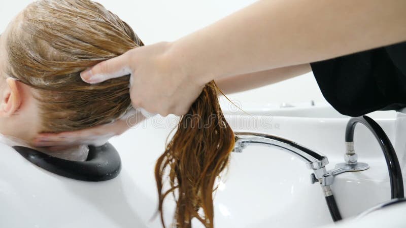 Στούντιο ομορφιάς Πλύσιμο γυναικείων μαλλιών με σαμπουάν, μακιγιάζ και σαλόνι ομορφιάς Κοντινό χέρι κομμωτή που πλένει μαλλιά φιλμ μικρού μήκους