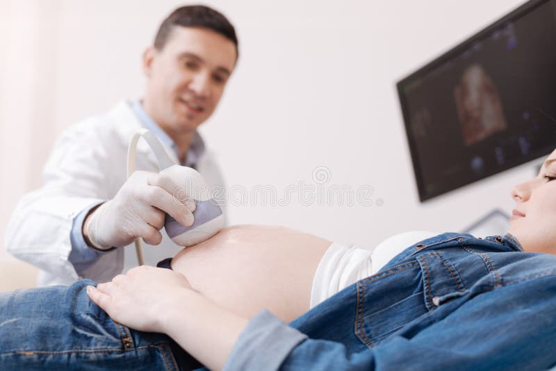 Συγκεντρωμένος παθολόγος που παρέχει την έγκυο υπομονετική εξέταση υπερήχου στην εργασία στοκ εικόνα με δικαίωμα ελεύθερης χρήσης Συγκεντρωμένος παθολόγος που παρέχει την έγκυο υπομονετική εξέταση υπερήχου στην εργασία στοκ εικόνα με δικαίωμα ελεύθερης χρήσης