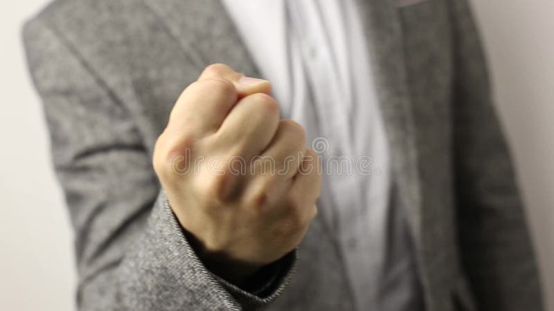Συμπαγής άνδρας με γκρι μπουφάν σε λευκό φόντο τραβώντας γροθιά προς τα επάνω Χειρονομία απειλής, έννοια επιθετικότητας, προειδοπ φιλμ μικρού μήκους