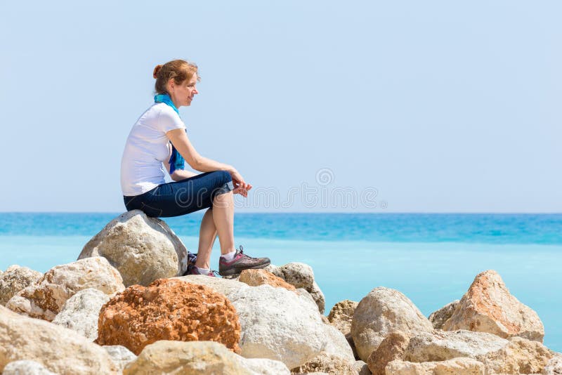 Συνεδρίαση γυναικών στους βράχους με τον μπλε θαλάσσιο ορίζοντα