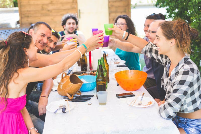 Συνεδρίαση ομάδας ανθρώπων που έχει το μεσημεριανό γεύμα μαζί και που ψήνει στοκ εικόνες Συνεδρίαση ομάδας ανθρώπων που έχει το μεσημεριανό γεύμα μαζί και που ψήνει στοκ εικόνες
