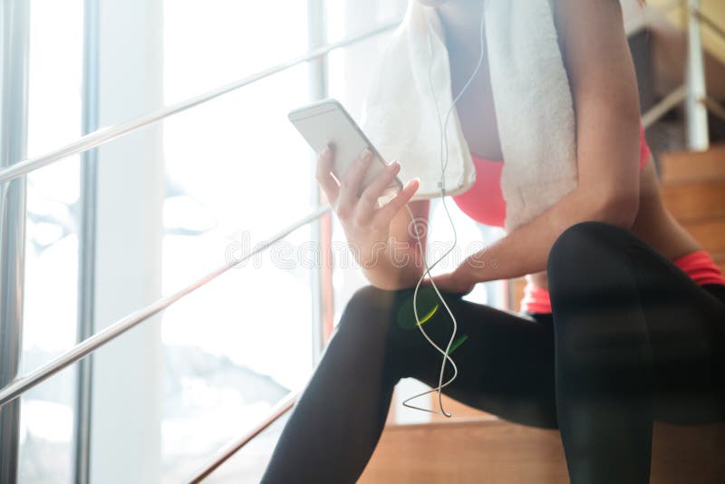 Συνεδρίαση φιλάθλων και χρησιμοποίηση του smartphone με τα ακουστικά στη γυμναστική στοκ εικόνες Συνεδρίαση φιλάθλων και χρησιμοποίηση του smartphone με τα ακουστικά στη γυμναστική στοκ εικόνες