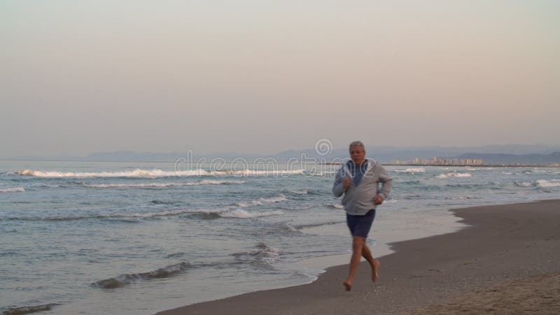 συνταξιούχος κάνει τζόκινγκ στην παραλία το ηλιοβασίλεμα