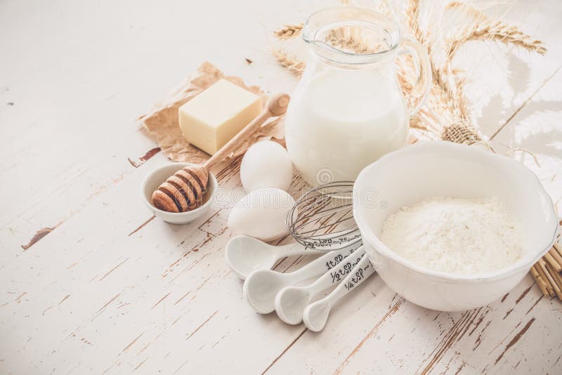 Ingredients for baking - milk butter eggs flour wheat, white wood background, copy space, toned. Ingredients for baking - milk butter eggs flour wheat, white wood background, copy space, toned