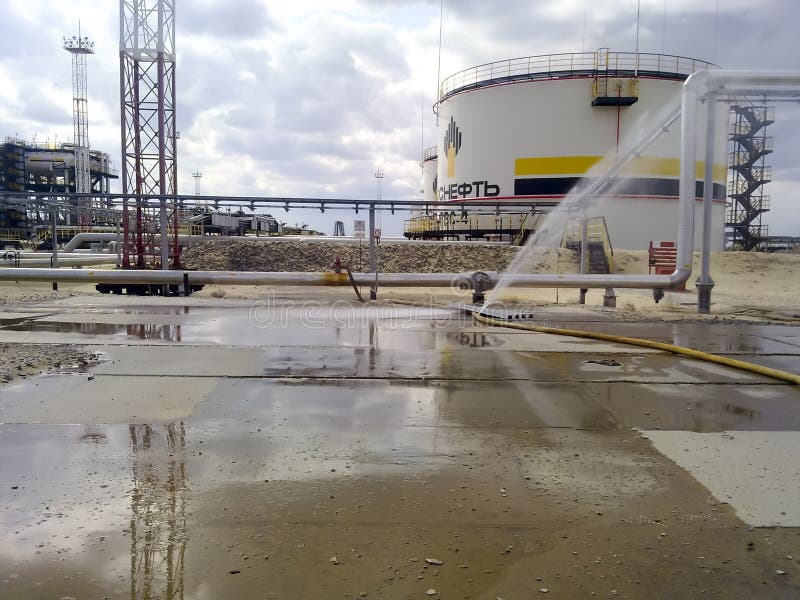 Σχισμένη μάνικα της μάνικας πυρκαγιάς Το νερό γέμισε το συγκεκριμένο πεζοδρόμιο Δεξαμενή και σωληνώσεις πετρελαίου Πετρελαιοφόρες στοκ εικόνα Σχισμένη μάνικα της μάνικας πυρκαγιάς Το νερό γέμισε το συγκεκριμένο πεζοδρόμιο Δεξαμενή και σωληνώσεις πετρελαίου Πετρελαιοφόρες στοκ εικόνα