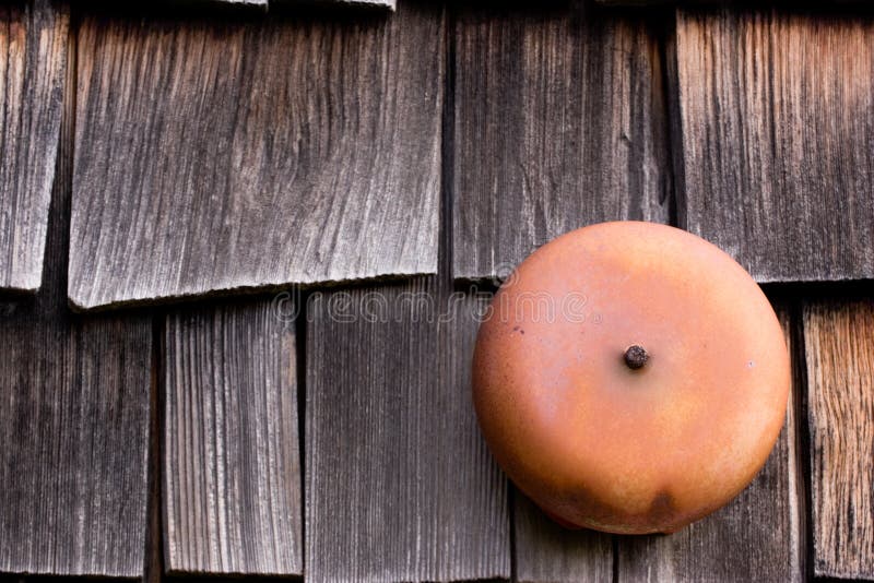 An old red school bell on a shingled wall. An old red school bell on a shingled wall