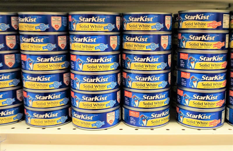 Metal supermarket shelf supports multiple columns of blue and yellow containers of solid white tunafish meat each encased and enclosed in cylindrical can. Metal supermarket shelf supports multiple columns of blue and yellow containers of solid white tunafish meat each encased and enclosed in cylindrical can.