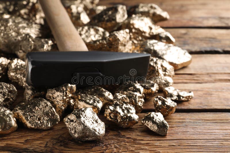 σωρός από χρυσά ψήγματα και σφυρί σε ξύλινο τραπέζι στοκ φωτογραφία με δικαίωμα ελεύθερης χρήσης