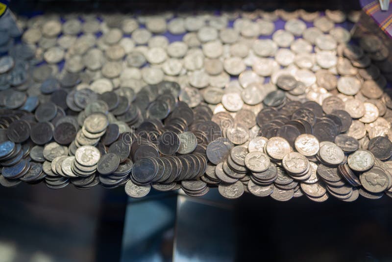 Pile of quarter coins inside of the gambling arcade machine at the amusement park. Pile of quarter coins inside of the gambling arcade machine at the amusement park.