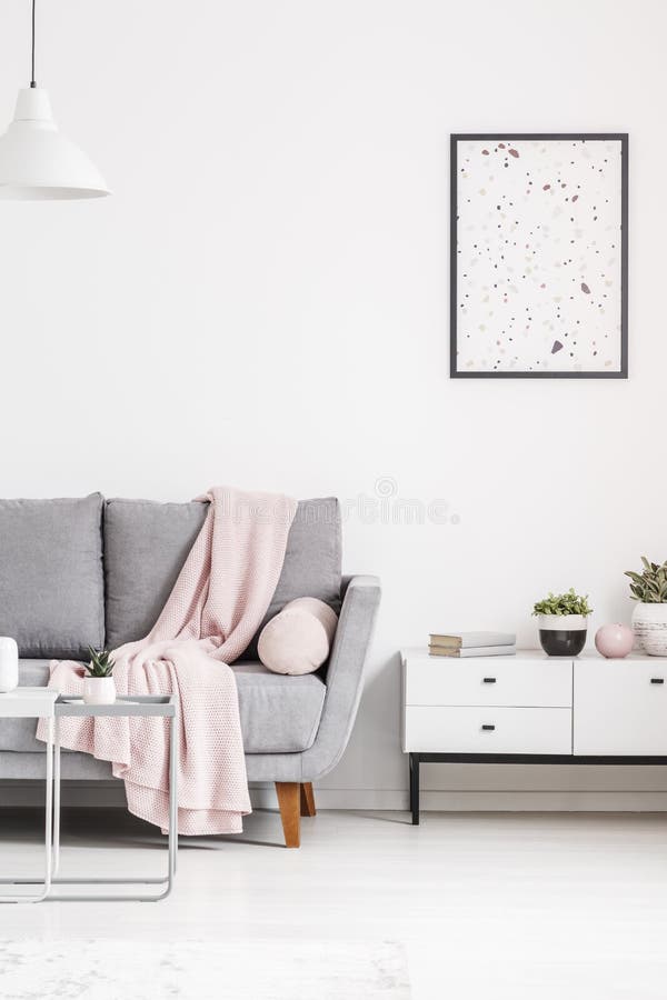 Modern poster on a white wall, grey sofa with blanket and cabinet in a living room interior. Real photo concept. Modern poster on a white wall, grey sofa with blanket and cabinet in a living room interior. Real photo concept