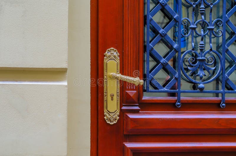 σύγχρονη καφέ ξύλινη πόρτα με χρυσό μοτίβο κλειδαριά με λαβή. το παράθυρο στην πόρτα είναι κλειστό με μεταλλικό μοτίβο στοκ φωτογραφίες με δικαίωμα ελεύθερης χρήσης