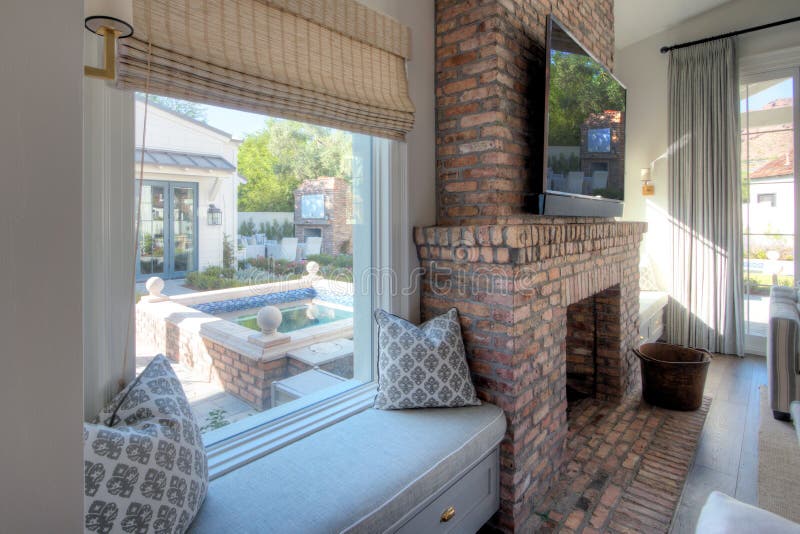 Modern living room space with lovely custom cushioned seating, brick fireplace, big screen tv, and view. Modern living room space with lovely custom cushioned seating, brick fireplace, big screen tv, and view.