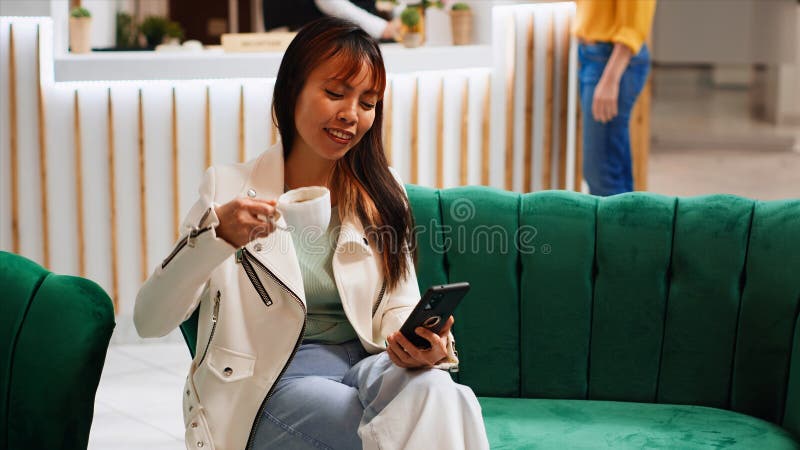 Modern person taking advantage of free wifi in lobby, using smartphone to pass time before going through check in process. Asian woman scrolling on social media apps, tourism concept. Modern person taking advantage of free wifi in lobby, using smartphone to pass time before going through check in process. Asian woman scrolling on social media apps, tourism concept.