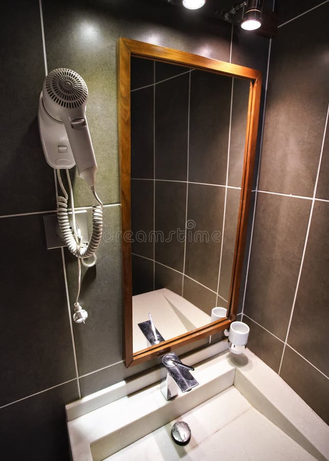 Modern bathroom in hotel room, white porcelain wash basin, mirror and hair dryer on the wall. Wide angle photo. Modern bathroom in hotel room, white porcelain wash basin, mirror and hair dryer on the wall. Wide angle photo