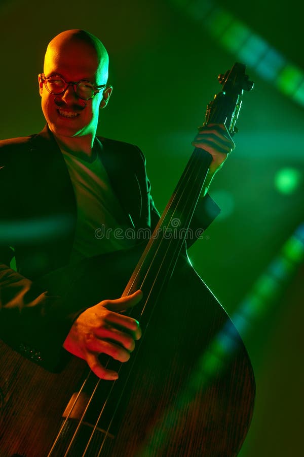 Contemporary double bass player in silhouette in red-green neon light against gradient studio background. Concept of music and art, hobby, concerts and festivals, modern culture. Ad. Contemporary double bass player in silhouette in red-green neon light against gradient studio background. Concept of music and art, hobby, concerts and festivals, modern culture. Ad