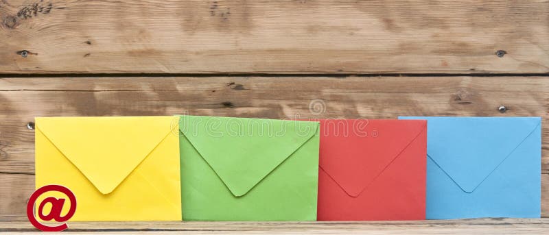 E-mail symbol and colorful envelopes on old wooden background. E-mail symbol and colorful envelopes on old wooden background