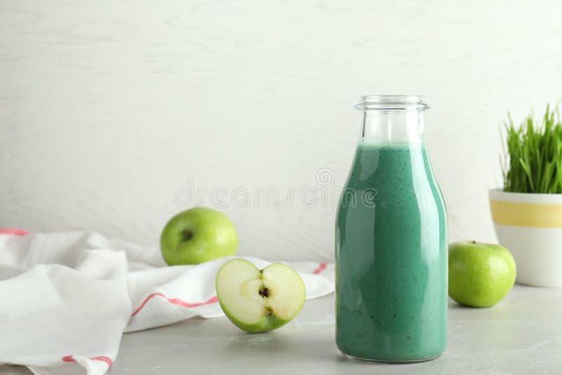 Σύνθεση με το μπουκάλι του καταφερτζή spirulina και των φρέσκων μήλων στον πίνακα στοκ φωτογραφία με δικαίωμα ελεύθερης χρήσης Σύνθεση με το μπουκάλι του καταφερτζή spirulina και των φρέσκων μήλων στον πίνακα στοκ φωτογραφία με δικαίωμα ελεύθερης χρήσης