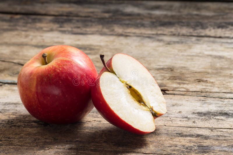 Σύνολο και περικοπή στη μισή Apple που βρίσκονται σε ξύλινο. Σύνολο και περικοπή στη μισή Apple που βρίσκονται στον κατασκευασμένο ξεπερασμένο ξύλινο πίνακα