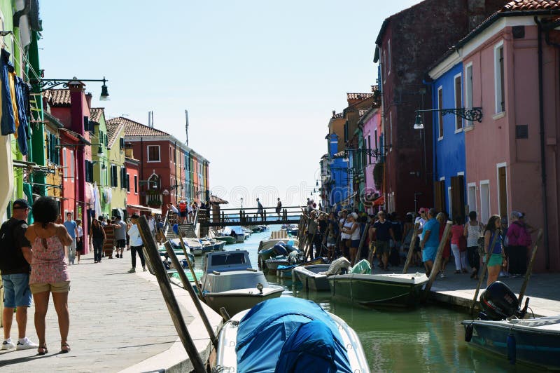 Σύνολο της Βενετίας Burano των τουριστών με τα χαρακτηριστικές ζωηρόχρωμες σπίτια, τις βάρκες και τη γέφυρά του στο κατώτατο σημε στοκ εικόνες με δικαίωμα ελεύθερης χρήσης Σύνολο της Βενετίας Burano των τουριστών με τα χαρακτηριστικές ζωηρόχρωμες σπίτια, τις βάρκες και τη γέφυρά του στο κατώτατο σημε στοκ εικόνες με δικαίωμα ελεύθερης χρήσης