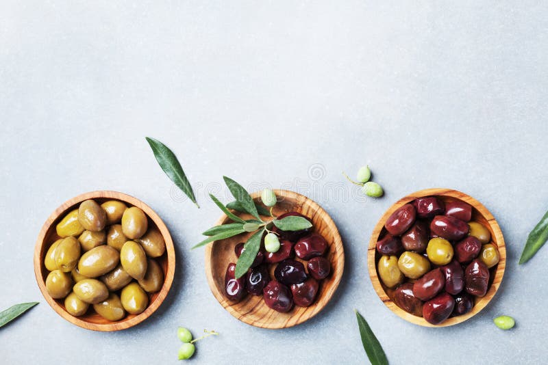 Σύνολο από τις ελιές στα ξύλινα κύπελλα που διακοσμούνται με τη φρέσκια τοπ άποψη κλάδων ελιών στοκ φωτογραφία