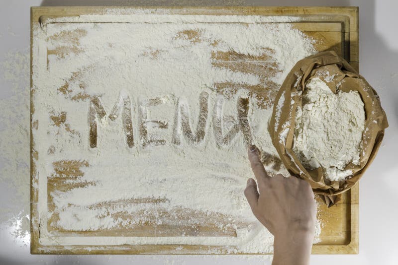 Τέμνων πίνακας με το αλεύρι και το γράψιμο και το χέρι επιλογών στοκ εικόνες Τέμνων πίνακας με το αλεύρι και το γράψιμο και το χέρι επιλογών στοκ εικόνες
