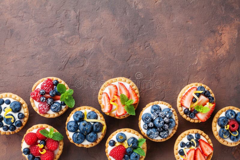 Τα εύγευστο tartlets ή το κέικ μούρων με το τυρί κρέμας διακόσμησαν τη φλούδα λεμονιών και το φύλλο μεντών άνωθεν Νόστιμα επιδόρπ στοκ φωτογραφία με δικαίωμα ελεύθερης χρήσης Τα εύγευστο tartlets ή το κέικ μούρων με το τυρί κρέμας διακόσμησαν τη φλούδα λεμονιών και το φύλλο μεντών άνωθεν Νόστιμα επιδόρπ στοκ φωτογραφία με δικαίωμα ελεύθερης χρήσης