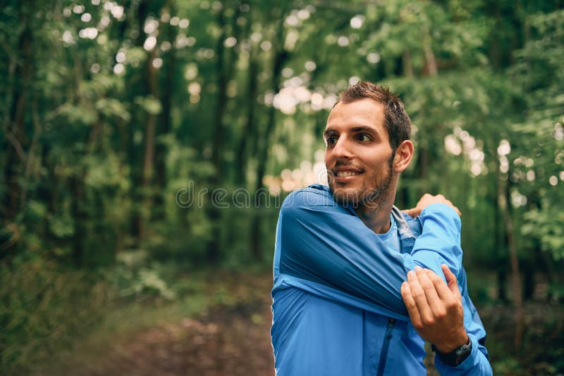 Τα κατάλληλα αρσενικά τεντώματα jogger κατά τη διάρκεια της κατάρτισης ημέρας για το διαγώνιο δασικό ίχνος χωρών συναγωνίζονται σ στοκ φωτογραφία με δικαίωμα ελεύθερης χρήσης Τα κατάλληλα αρσενικά τεντώματα jogger κατά τη διάρκεια της κατάρτισης ημέρας για το διαγώνιο δασικό ίχνος χωρών συναγωνίζονται σ στοκ φωτογραφία με δικαίωμα ελεύθερης χρήσης