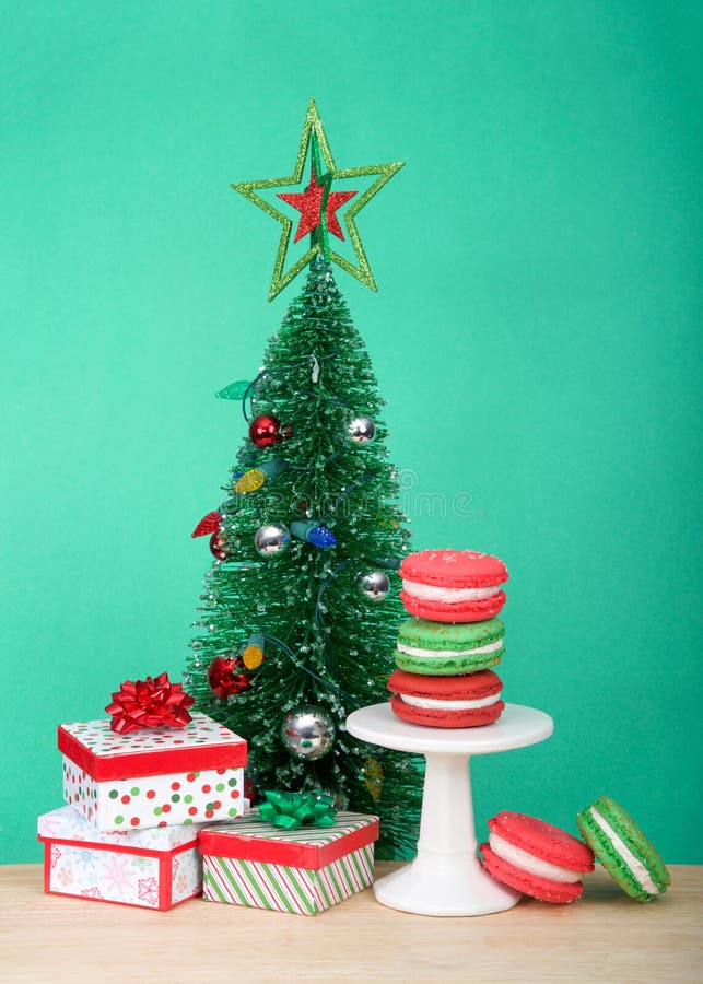 Τα μπισκότα Χριστουγέννων macaron σε ένα μικρό βάθρο με το χριστουγεννιάτικο δέντρο και παρουσιάζουν στοκ εικόνες Τα μπισκότα Χριστουγέννων macaron σε ένα μικρό βάθρο με το χριστουγεννιάτικο δέντρο και παρουσιάζουν στοκ εικόνες