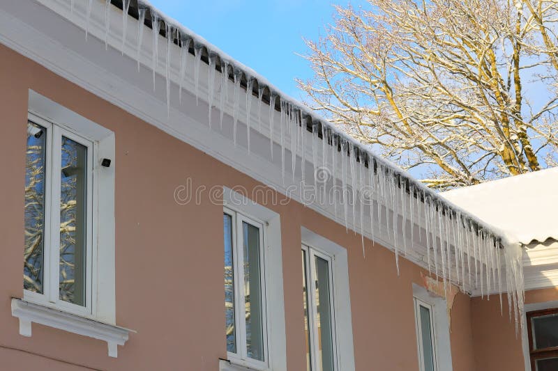 τα παγάκια σχηματίζονται με χάρη σε ένα άνετο σπίτι κάτω από έναν καθαρό και όμορφο γαλάζιο ουρανό στοκ εικόνες