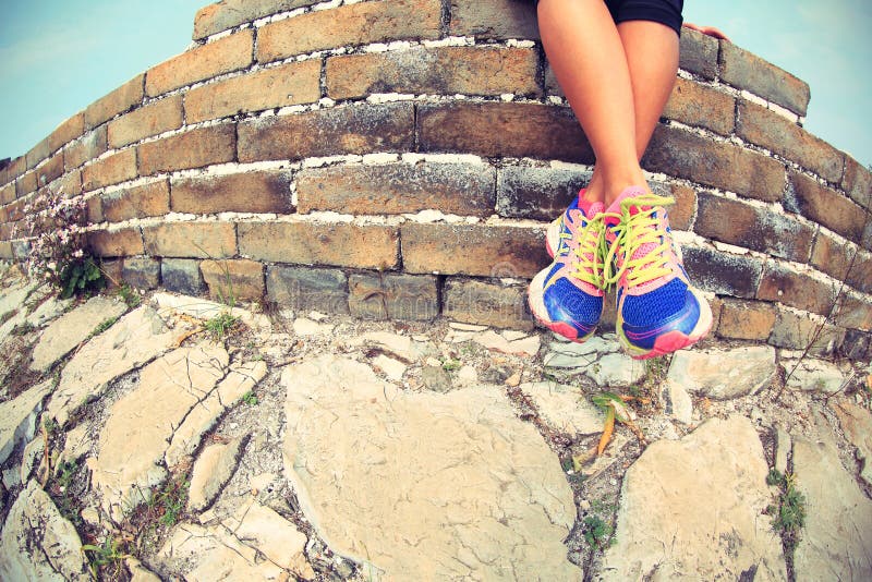 Ftiness woman runner legs sit on great wall. Ftiness woman runner legs sit on great wall