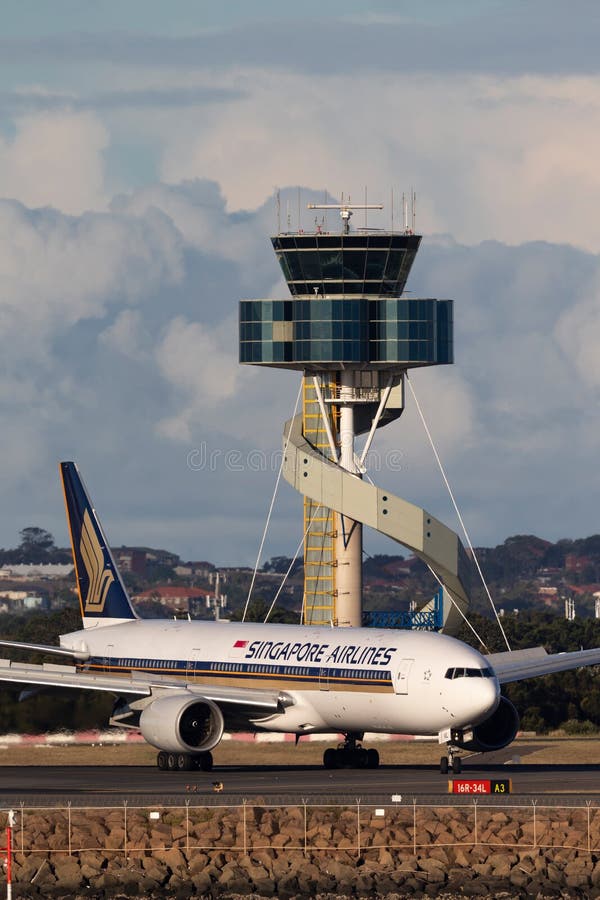 Ταξί αεροσκαφών της Singapore Airlines Boeing 777 μετά από να προσγειωθεί στον αερολιμένα του Σίδνεϊ με τον πύργο ελέγχου εναέρια στοκ φωτογραφία