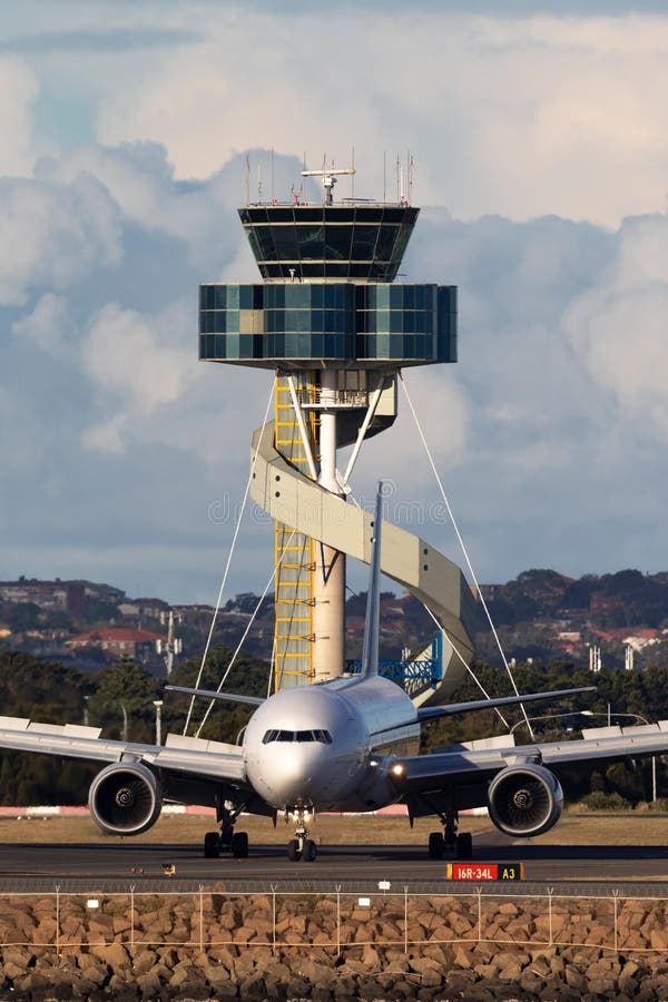 Ταξί αεροσκαφών της Singapore Airlines Boeing 777 μετά από να προσγειωθεί στον αερολιμένα του Σίδνεϊ με τον πύργο ελέγχου εναέρια στοκ εικόνες