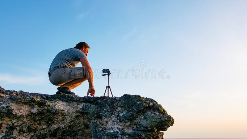 Ταξίδι videographer που κάνει το βίντεο στην κορυφή του απότομου βράχου κατά τη διάρκεια του χρόνου ηλιοβασιλέματος στοκ φωτογραφία με δικαίωμα ελεύθερης χρήσης Ταξίδι videographer που κάνει το βίντεο στην κορυφή του απότομου βράχου κατά τη διάρκεια του χρόνου ηλιοβασιλέματος στοκ φωτογραφία με δικαίωμα ελεύθερης χρήσης